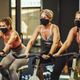 people cycling in a gym with masks on